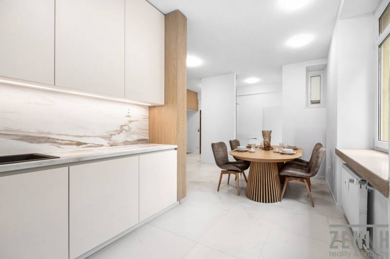 A kitchen with a dining table and four chairs in a 3-room apartment.