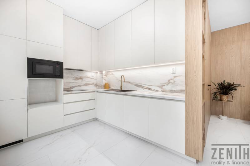 A kitchen in a 3-room apartment with white cabinets and a marble countertop.