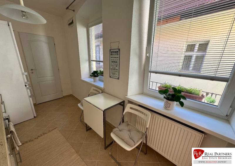 A kitchen with windows, a table with chairs, flowers on the windowsill, a 2-room apartment.