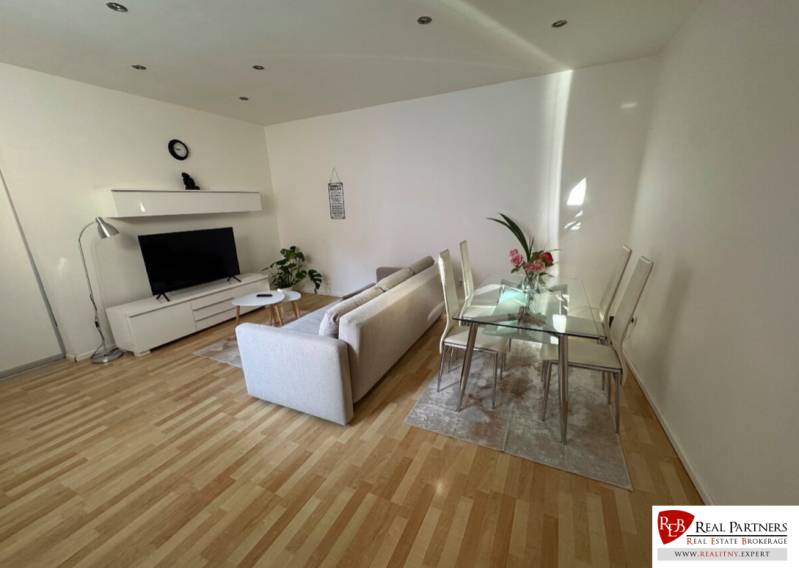 Living room with a sofa, television, and glass table in a two-room apartment.