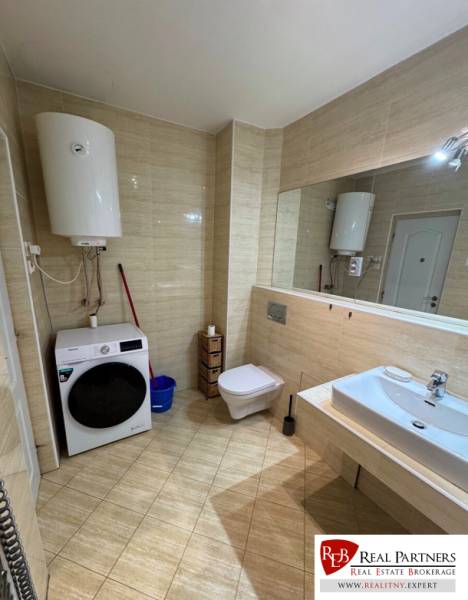 Bathroom with a boiler, washing machine, toilet, and mirror in a 2-room apartment.