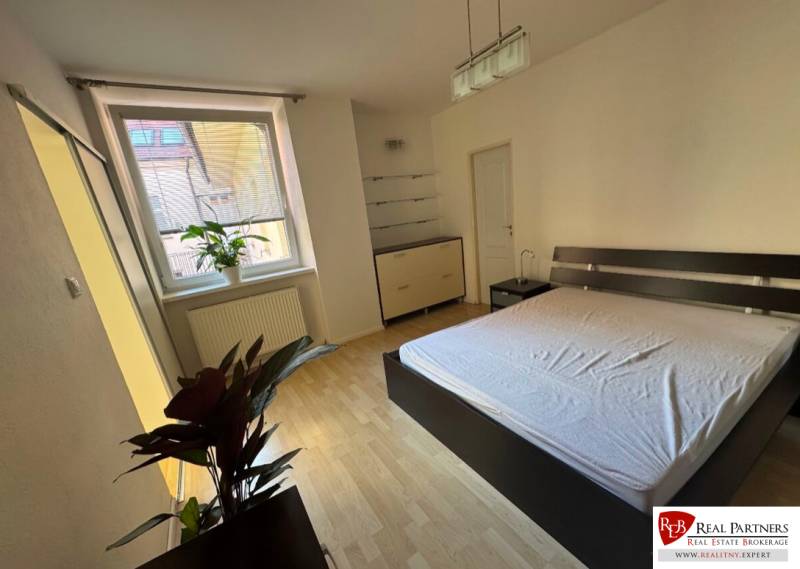 A bright bedroom with a large window and a double bed in a 2-room apartment.