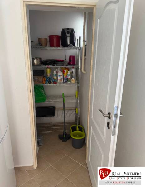 Storage room in a 2-room apartment with shelves and cleaning supplies.