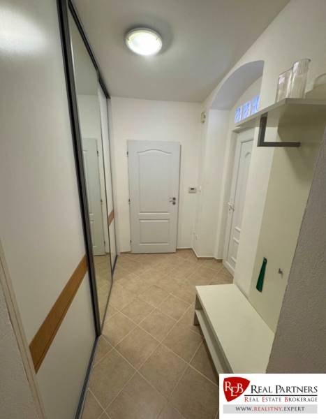 A hallway in a 2-room apartment with a built-in wardrobe and a bench, neutral design.