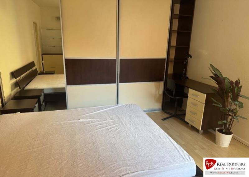 Bedroom in a two-room apartment with a bed, desk, and wardrobe.
