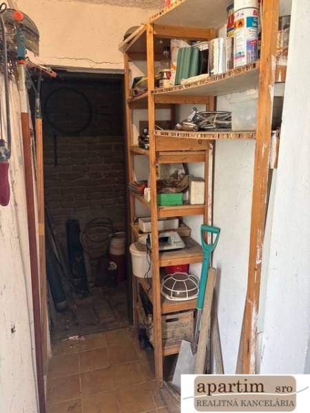 A small room with a storage rack, a shovel, and gardening tools. Premises - living.