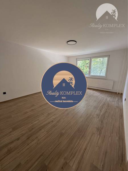 A spacious room with a wooden floor and a large window in a 3-room apartment.