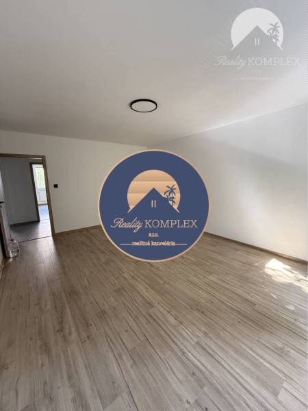 A room with a wooden floor in a 3-room apartment, with one window and an entrance door.