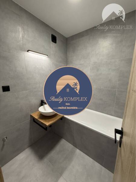 A bathroom in a 3-room apartment with a bathtub and a sink on a wooden countertop.