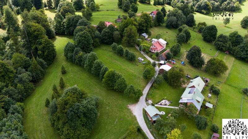 Aerial view of recreational plots in Oščadnica surrounded by dense greenery and houses.