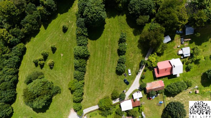 Aerial view of recreational plots in Oščadnica with greenery, buildings, and a road.