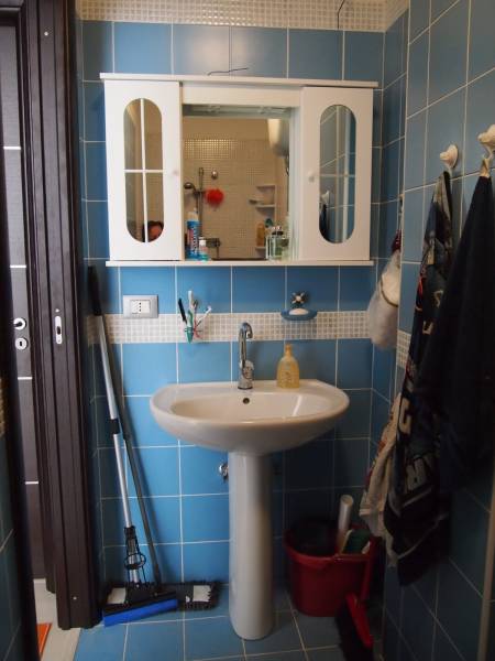 Bathroom in a 3-room apartment with blue tiles, a sink, and a wall cabinet.