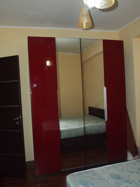 A wardrobe with red doors and a mirror in a 3-room apartment with a bedroom.