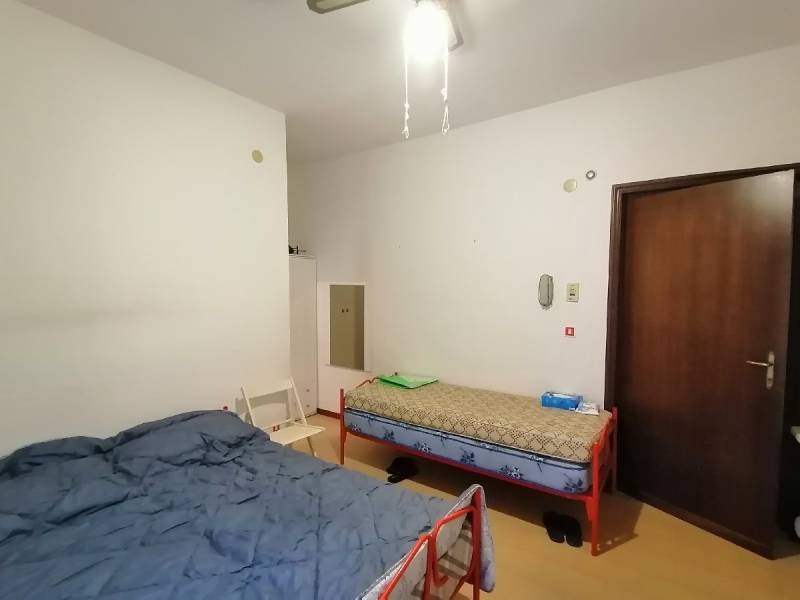 Two beds and a chair in the room of a studio apartment.