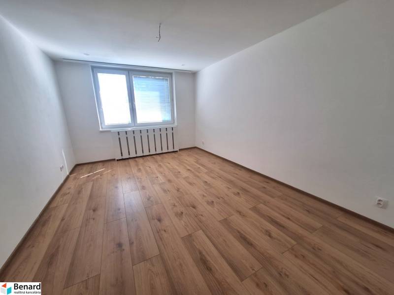 An empty room with a wooden floor and a large window, in a 2-room apartment.