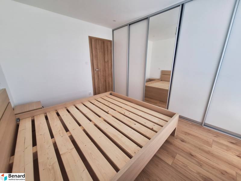 Bedroom with a wooden bed and a built-in wardrobe in a 2-room apartment.