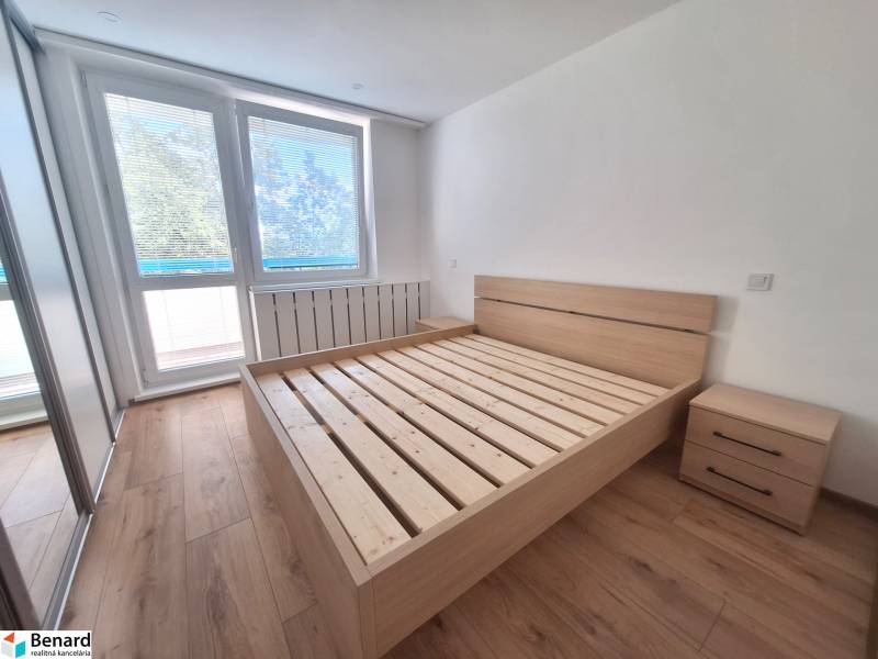 A bright bedroom with a wooden bed and nightstands in a two-room apartment.