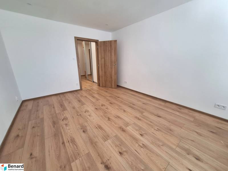 Empty room with wooden floor and closed doors in a two-room apartment.