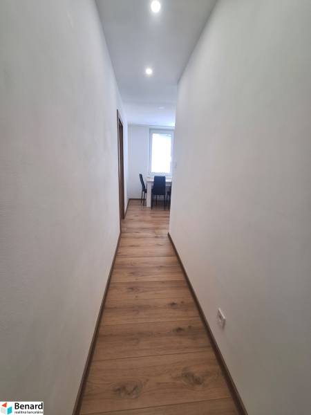A hallway in a 2-room apartment with wooden flooring and ceiling lights.