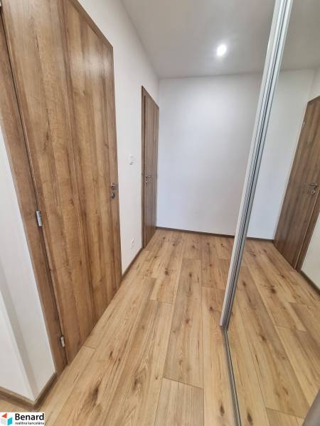 A hallway in a 2-room apartment with a wooden floor and a mirrored wardrobe.