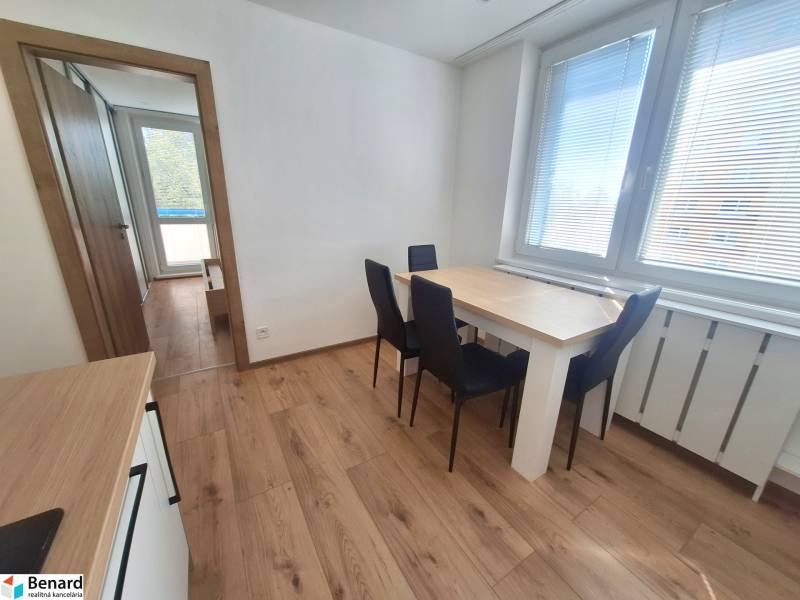 Dining area with a wooden table and chairs in a 2-room apartment.