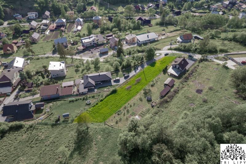 An aerial view of residential plots in the village of Raková, green slopes and houses.