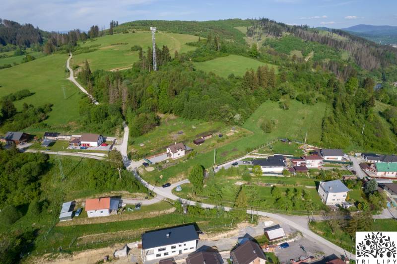 Aerial view of residential plots in Raková, surrounded by green hills and houses.