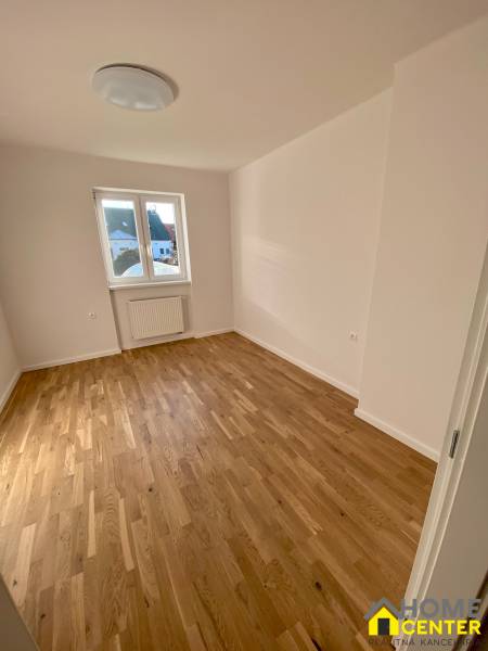 A room in a 3-room apartment with a wooden floor and a large window.