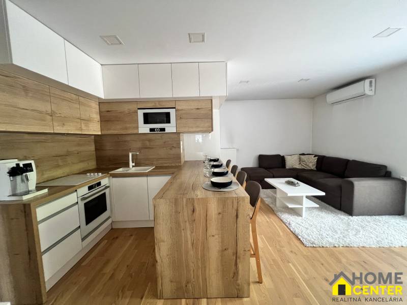 A kitchen connected to the living room in a 3-room apartment, with wooden details and seating.