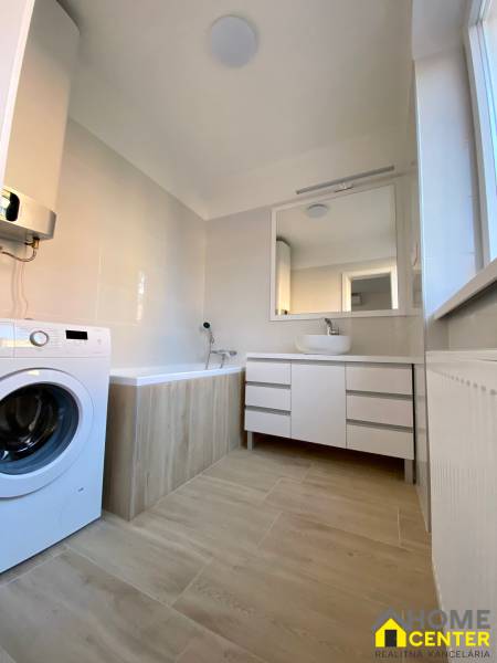 A bathroom in a 3-room apartment with a bathtub, washing machine, and mirrored cabinet.