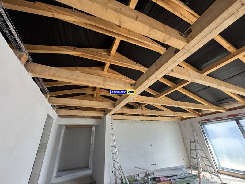 The family house has white plaster, wooden beams, and an unfinished ceiling.