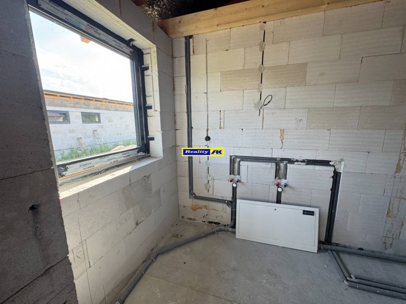 Unfinished room in a family house with concrete walls and a window.