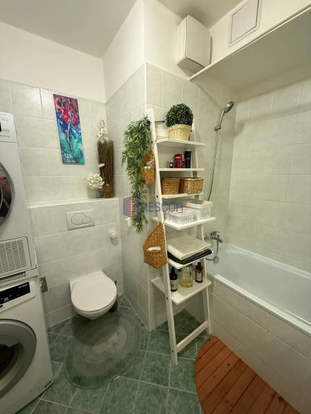 Bathroom with a washing machine, bathtub, and decorations in a 2-room apartment.