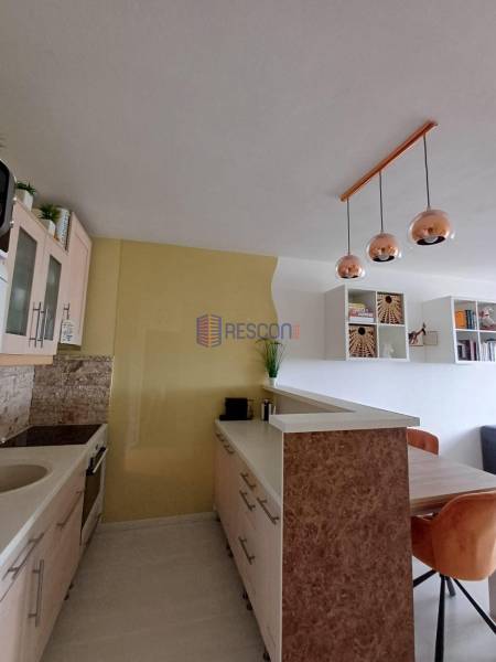 A kitchen in a 2-room apartment with hanging lights and a wooden table.