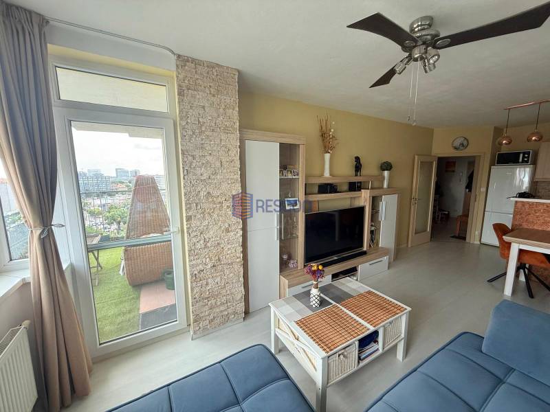 Living room in a 2-room apartment with a balcony, TV wall, and ceiling fan.
