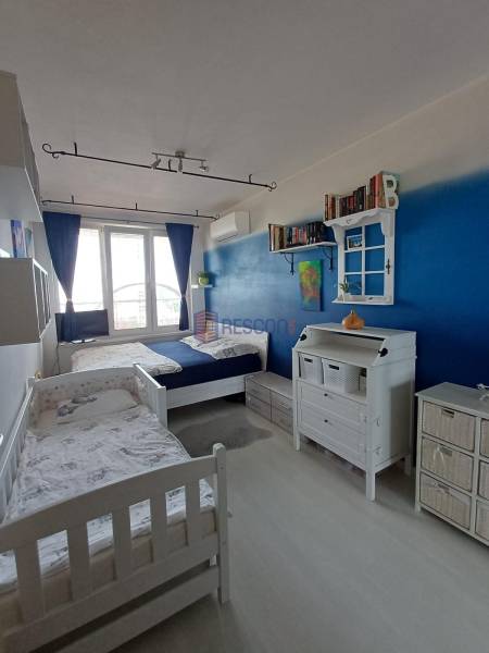 Children's room with two beds, a blue wall, and plenty of storage space.
