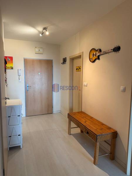 Entrance hallway in a 2-room apartment with a wooden bench and a decorative guitar on the wall.