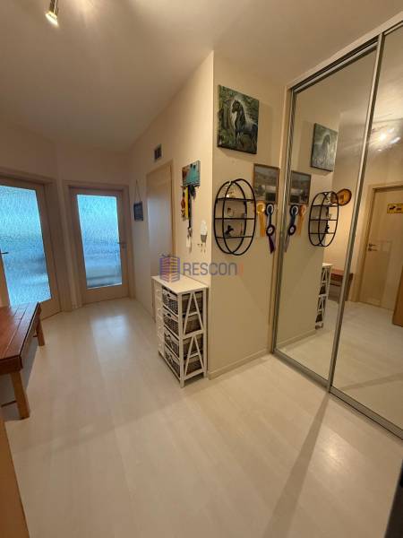 A hallway in a 2-room apartment with white furniture and a mirrored wardrobe.