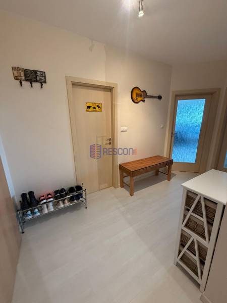 Hallway of a 2-room apartment with a shoe cabinet, bench, and wall decoration.