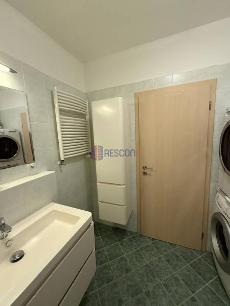 A bathroom in a 2-room apartment with a sink, a washing machine, and a green floor.