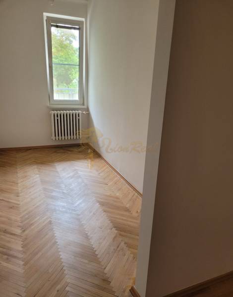 A room in a 3-room apartment with a wooden floor and a radiator under the window.