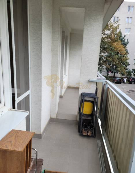 A balcony in a 3-room apartment with folding chairs and a view of the trees in the yard.