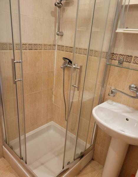 Shower corner and sink in the bathroom of a 3-room apartment with glass doors.