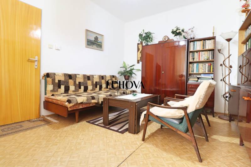Living room in a family house with wooden furniture, carpets, and a bookshelf.