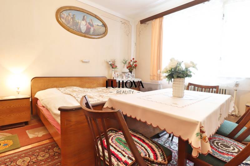 A bedroom in a family house with wooden furniture, floral decorations, and a painting above the bed.
