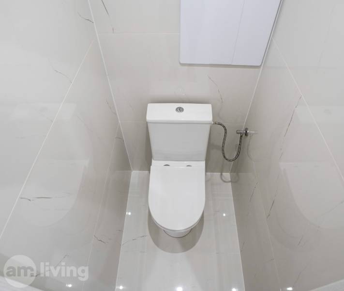 Bathroom in a 2-room apartment with white tiles and a toilet.