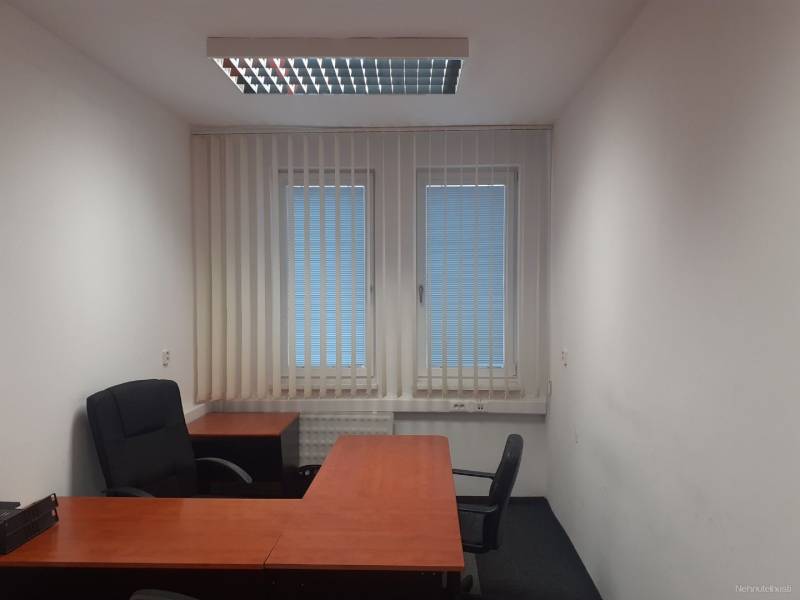 Offices with desks, black chairs, and blinds on the windows.