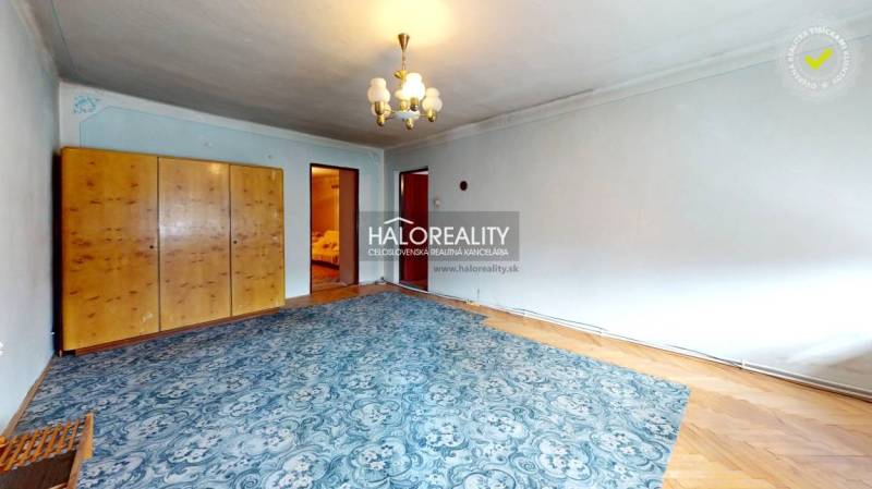 A room in a cottage with a carpeted floor, a wardrobe, a mirror, and a pendant light.