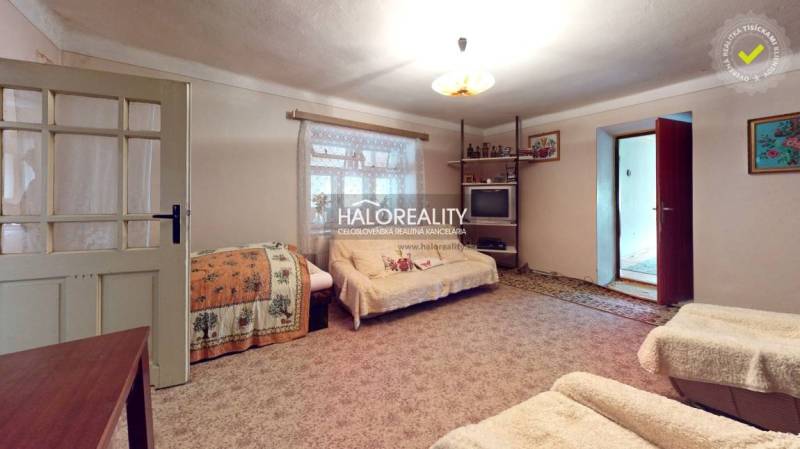 Living room in a cottage with comfortable sofas, a carpet, and a cabinet with porcelain.