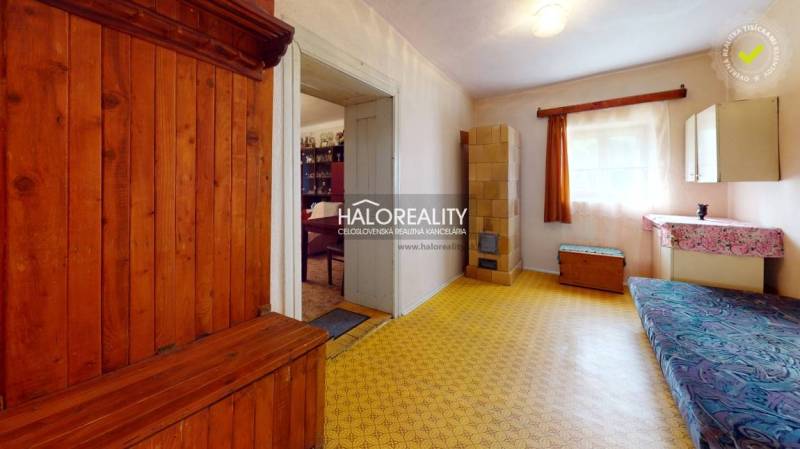 A room in a cottage with a wooden bed and a dressing table, a bright room with a large window.